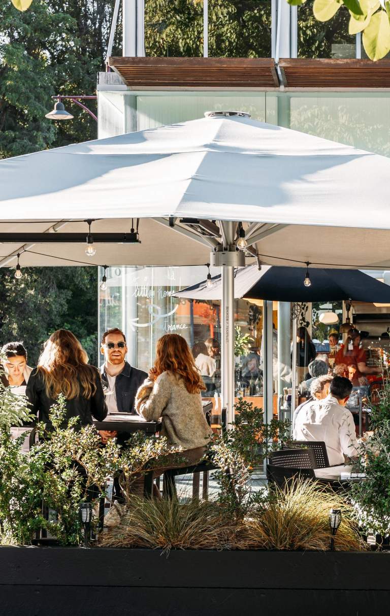 View of a people sitting in a cafe courtyard surrounded with greenery