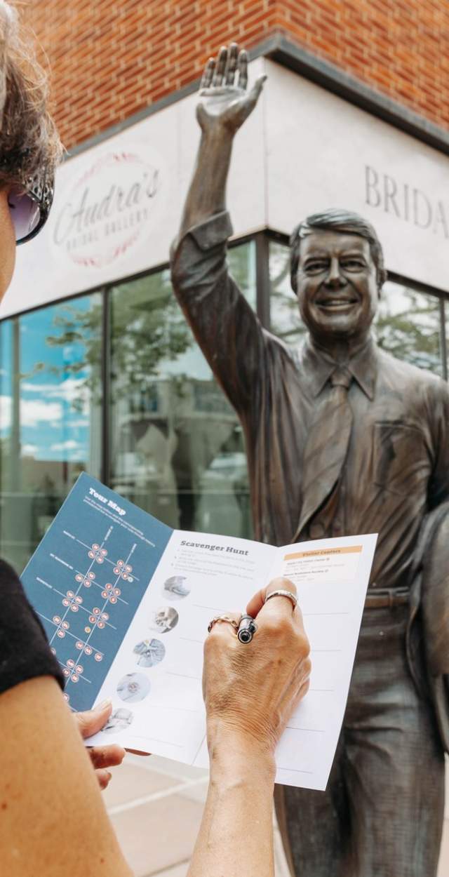 person filling out scavenger hunt in front of Jimmy Carter city of presidents statue in rapid city,sd