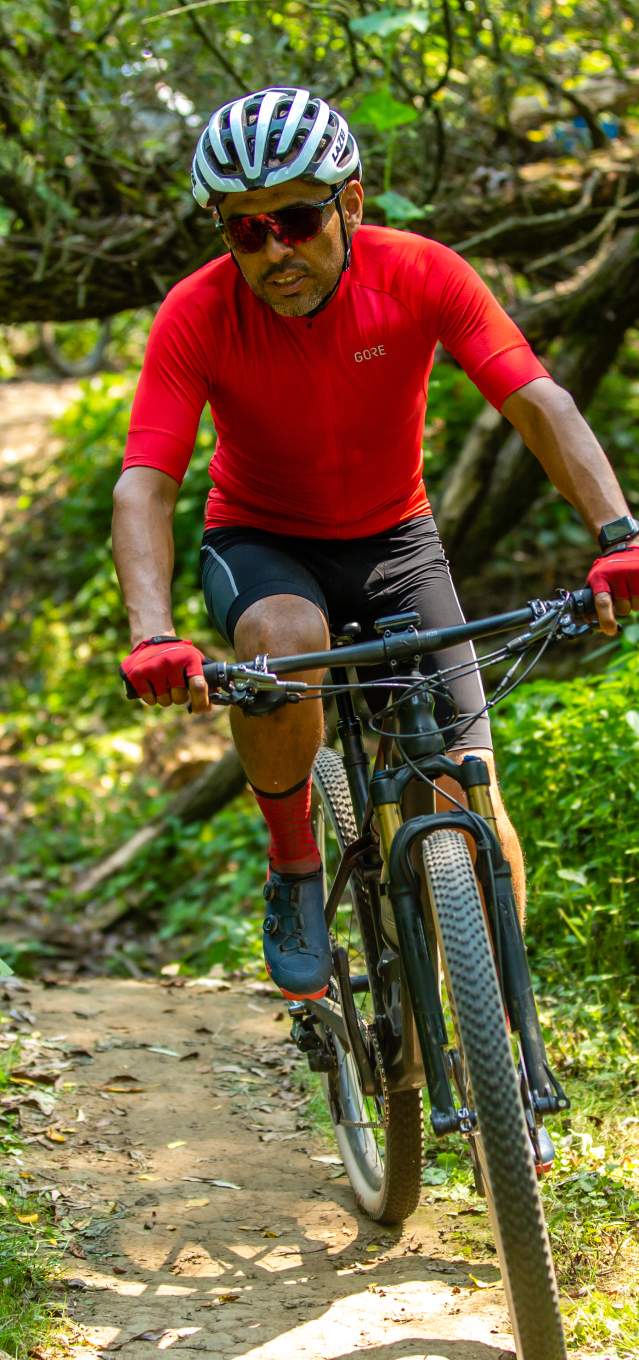 A man in a red shirt and helmet rides his bike on a trail