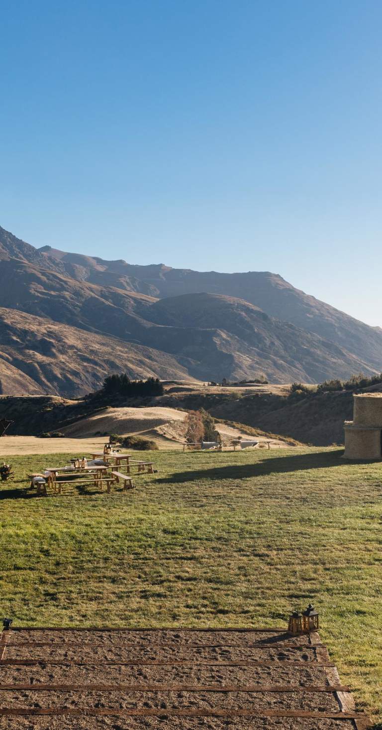 Tipi set up in field with mountains in the background