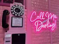 pink wall telephone beside a pink neon sign