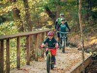 A family mountain biking through a trail in the fall at Clarksville's Rotary Park.