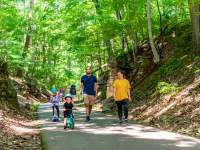 family with children on bikes walk the Clarksville Greenway