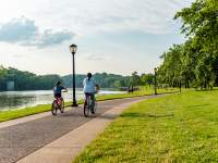two girls ride bikes along a paved path next to a river