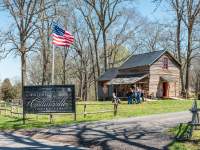 people outside of a historic log cabin