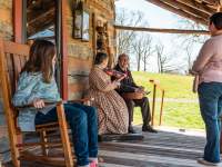 a young girl and woman enjoy music being played on the porch of a log cabin