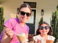 a woman and child enjoy ice cream cones in the grass