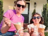 a woman and child enjoy ice cream cones in the grass