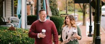 A couple walking hand in hand with coffee cups through the leaf covered, bricked lined streets of Historic Dublin in the fall.