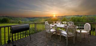 Landscape shot of sunset from the deck of a glamping tent with a set table and chairs in the foreground