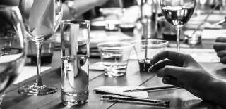 Black and white photograph of drinks and pens on a table