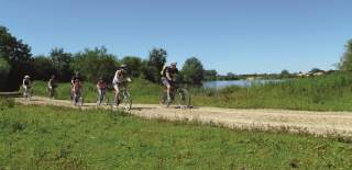 A group of people cycle alongside a lake