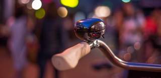 Photograph showing a bicycle handlebar with a traditional style bell mounted to it