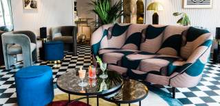 Three cocktails on a table in a stylish cocktail lounge with bold-print sofa and checkered floor at The Old Stocks Inn in the Cotswolds