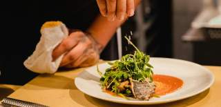 Photograph showing a chef putting the finishing touches to one of their dishes