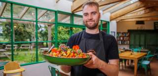A chef holds a large dish of food in the cafe at The Organic Farm Shop & Cafe, Abbey Home Farm