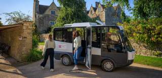 Visitors getting off of an electric shuttle bus at Kelmscott Manor