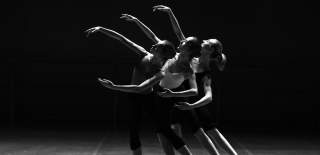 Black and white photograph showing three women holding a pose as they dance in synchronicity