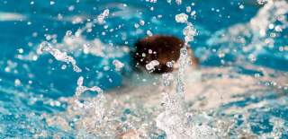 Photograph showing splashes in the water as a person swims in a pool