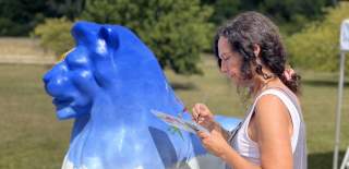 Louise Braithwaite painting a lion in the outdoors