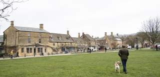 Man walking his dog across the green towards Broadway village centre