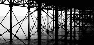 Black and white photograph looking out from underneath South Parade Pier