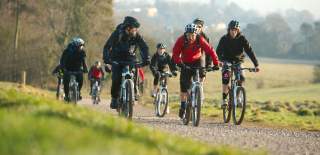 A group cycling on rented mountain bikes towards the off-road mountain biking trail at Ashton Court - credit Pedal Progression