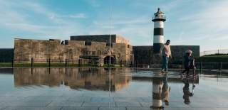 Photograph showing a parent and child at the water fountain outside Southsea Castle