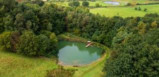 The spring-fed lake at Heath Farm Holiday Cottages surrounded by woodland and open fields