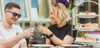 A couple clinking Champagne classes while they enjoy afternoon tea at Drewton's in East Yorkshire