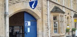 Large wooden gates painted blue in a Cotswold stone building, mark the entrance to the Visitor Information Centre in Chipping Campden