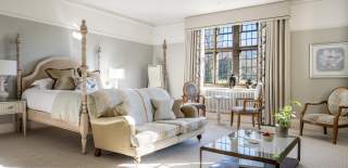 A four poster bed catches the morning light through a leaded window