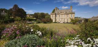 Bourton House stands infront of a large lawn bordered with flowers and trees