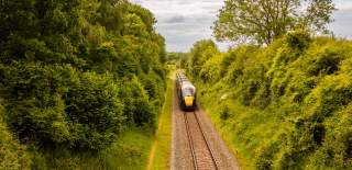 A train travels past trees in the Cotswolds