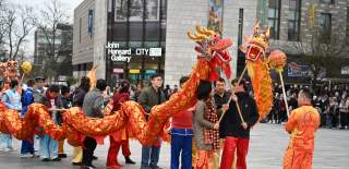 Group of people holding up paper dragon to perform lunar new year dragon dance