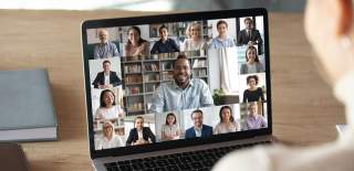A person sits infront of a laptop at an online meeting