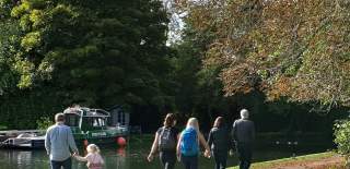 People walking along the Thames Path along the river.