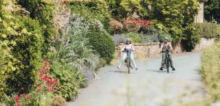 A couple free wheeling on bikes through Adlestrop