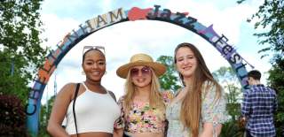Ladies stood in front of the Cheltenham Jazz Festival sign in Montpellier Gardens, Cheltenham.