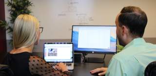 Photograph of two people working on computers