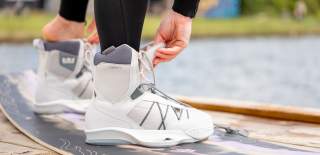 A close up shot of a wakeboarder putting on their boots