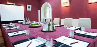 A meeting room with burgundy walls and modern equipment at Blenheim Palace in the Cotswolds