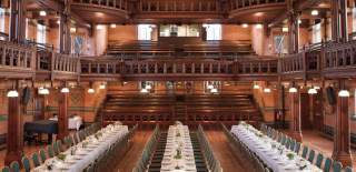 Long banqueting tables fill the length of a large wooden room with tiered balcony at Cheltenham Ladies College
