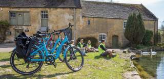 A group of cyclists sitting by a pond