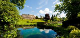The stunning, Grade II listed Cowley Manor mansion lies in the distance with lush green lawns in front leading down to a large pond