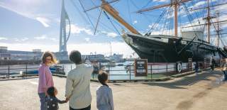 A family looks out at HMS Warrior, with the Spinnaker Tower in the background