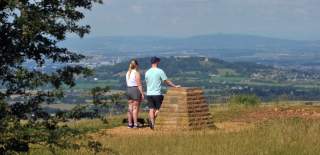 Two people on Leckhampton Hill, Cheltenham. Stood with backs to the camera, overlooking the view over Cheltenham, Gloucestershire.
