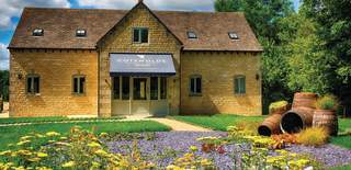 The Cotswolds Distillery visitor centre surrounded by flowers and trees