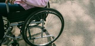 Photograph of a wheelchair user in a pink hoodie, sat in their chair