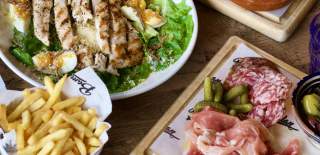 Selection of food dishes from above - grilled chicken, chips and a meat board